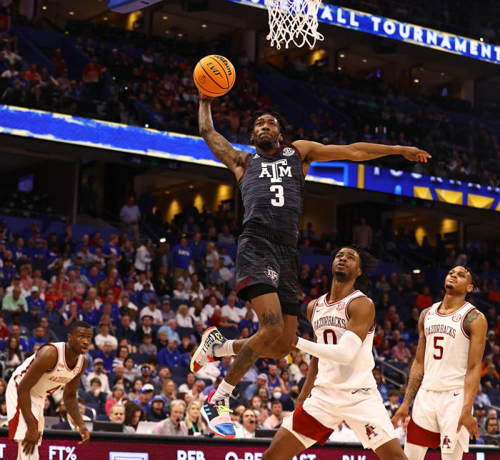 Three Arkansas Razorbacks stand by helplessly watching in frustration as Texas A&M guard Quenton Jackson executes one of several dunks the Hogs gave up down the stretch en route to an 82-64 loss.